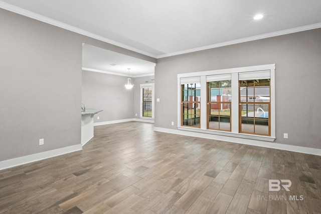 unfurnished living room with wood-type flooring, ornamental molding, and a notable chandelier