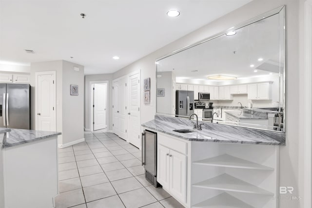 kitchen with sink, white cabinetry, light stone counters, kitchen peninsula, and stainless steel appliances