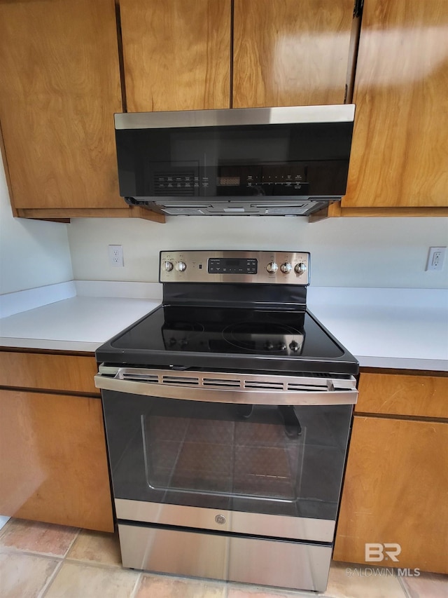 kitchen featuring stainless steel appliances, light countertops, brown cabinets, and modern cabinets