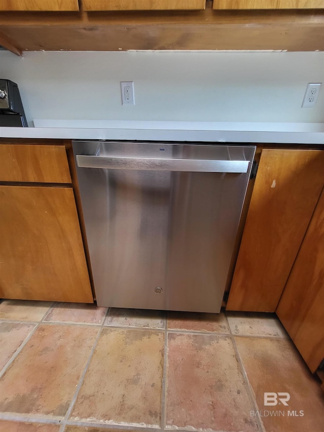 kitchen view of dishwasher, brown cabinetry, and light countertops
