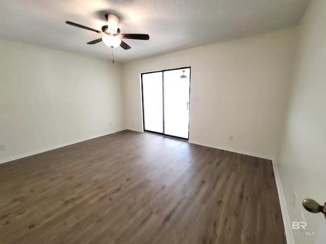 unfurnished room featuring dark wood-style flooring, ceiling fan, and baseboards