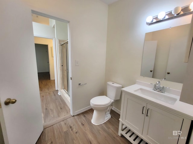 bathroom with wood finished floors, toilet, a stall shower, and vanity