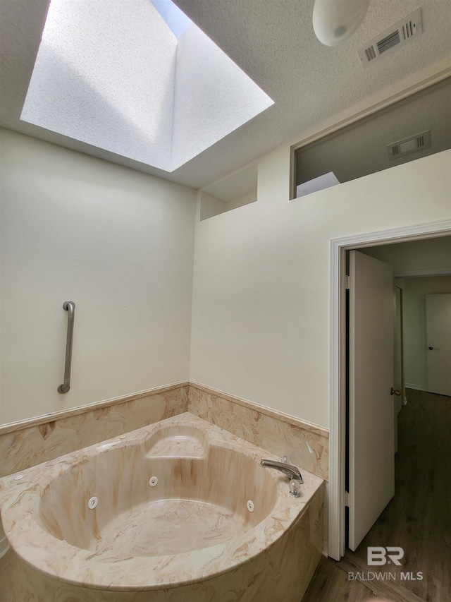 full bath featuring wood finished floors, a tub with jets, and a skylight