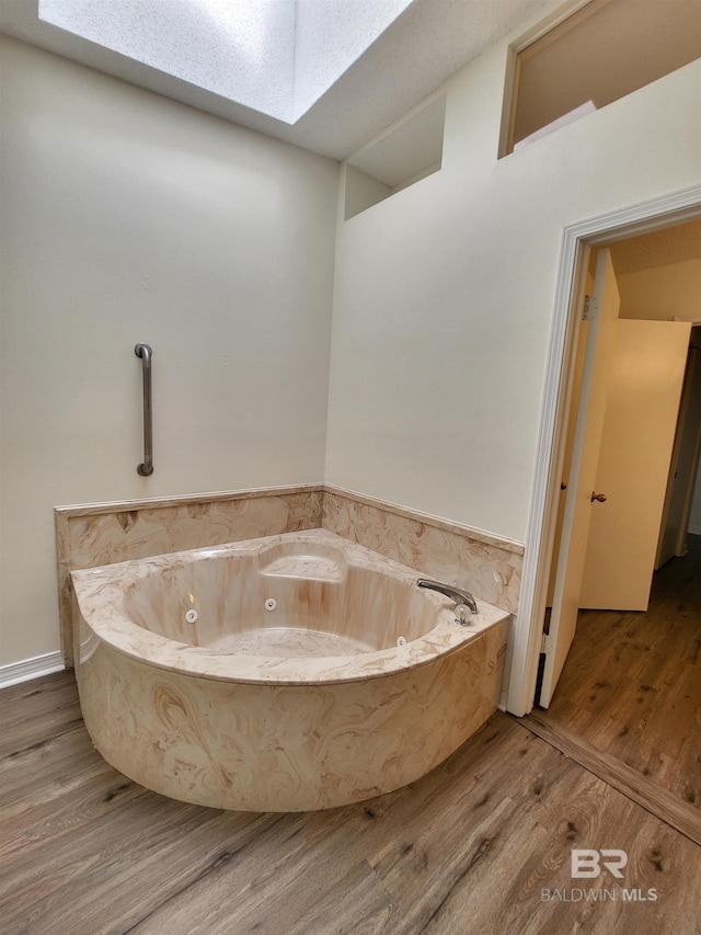 full bathroom with wood finished floors, a jetted tub, and a skylight