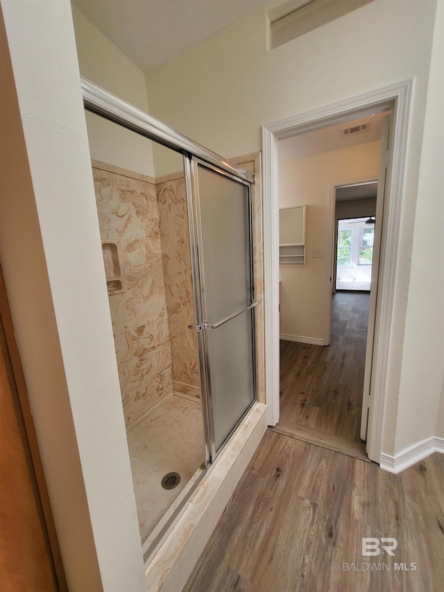 bathroom with wood finished floors, a stall shower, and baseboards