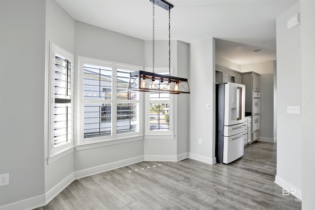 unfurnished dining area featuring a notable chandelier and light wood-type flooring