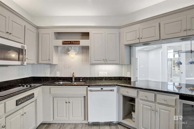 kitchen featuring white dishwasher, beverage cooler, dark stone countertops, and sink