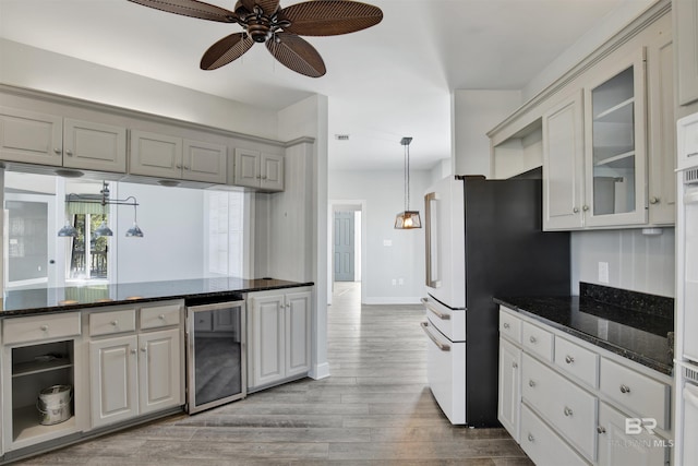 kitchen featuring light wood-type flooring, dark stone counters, ceiling fan, decorative light fixtures, and wine cooler