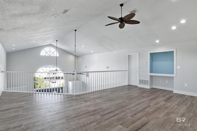 spare room with hardwood / wood-style floors, a textured ceiling, vaulted ceiling, and ceiling fan