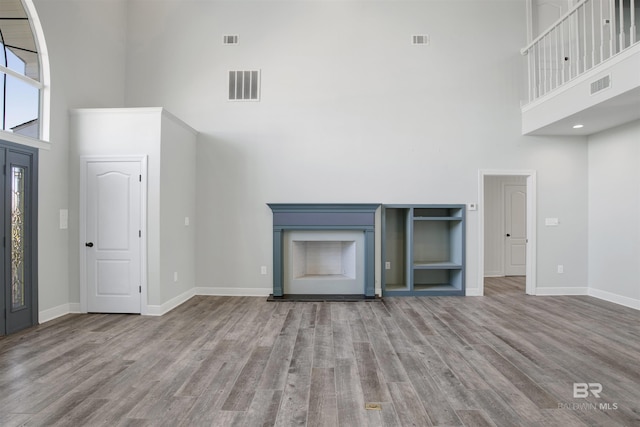 unfurnished living room featuring a towering ceiling and light hardwood / wood-style floors