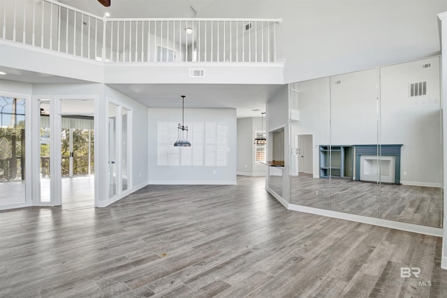 unfurnished living room featuring a high ceiling, ceiling fan, and wood-type flooring