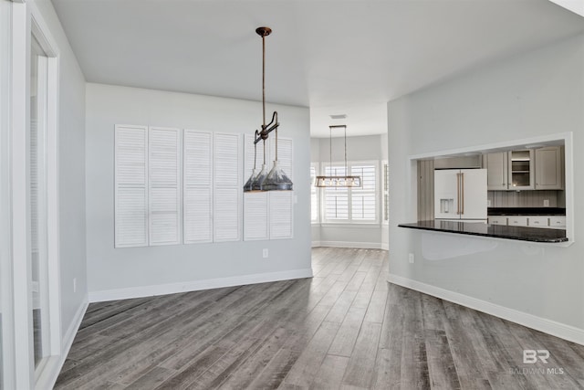 unfurnished dining area with hardwood / wood-style floors and an inviting chandelier