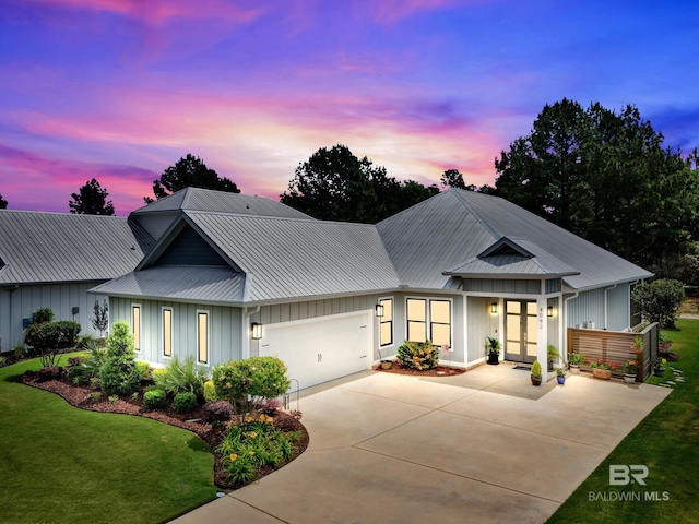 view of front of home featuring board and batten siding, an attached garage, concrete driveway, and metal roof