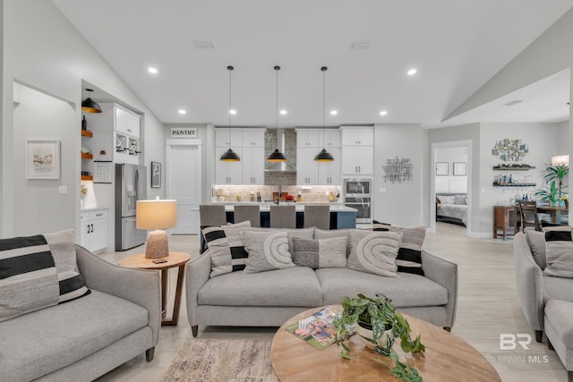 living area featuring visible vents, vaulted ceiling, light wood-type flooring, baseboards, and recessed lighting