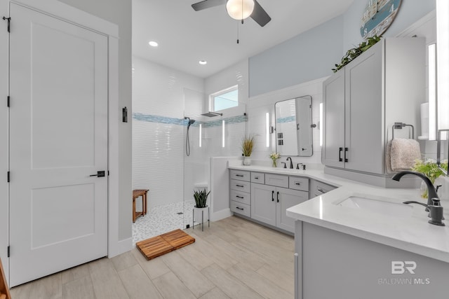 bathroom with a sink, a walk in shower, a ceiling fan, and two vanities