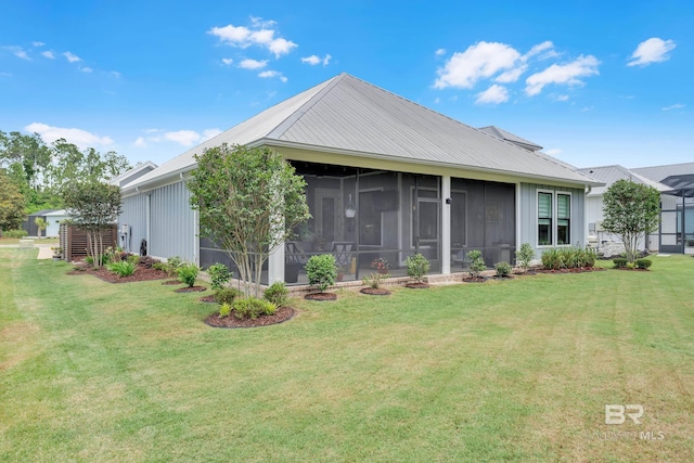 back of house with a sunroom, a yard, and metal roof