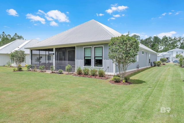 view of front of property featuring a sunroom, board and batten siding, a front yard, and metal roof