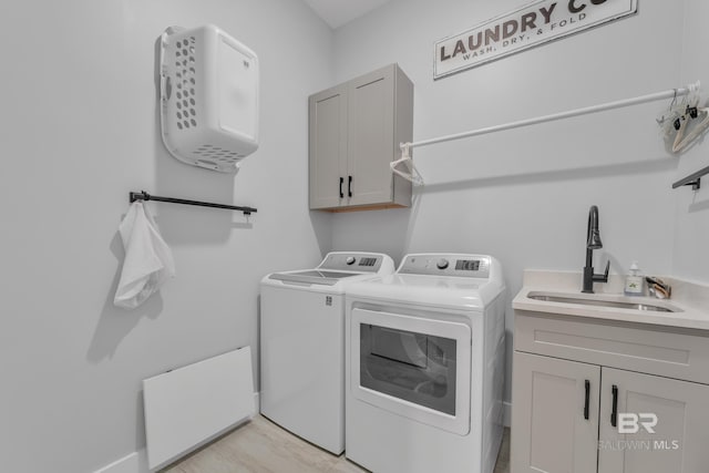 clothes washing area with a sink, cabinet space, and washing machine and clothes dryer