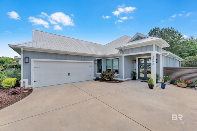view of front of house featuring an attached garage, board and batten siding, concrete driveway, french doors, and metal roof