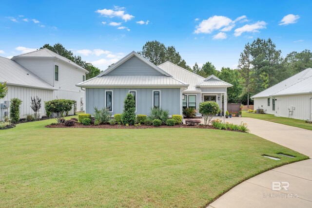 view of front facade with board and batten siding, driveway, metal roof, and a front lawn