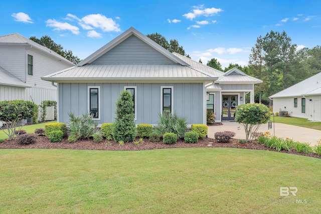 view of front of house featuring french doors, board and batten siding, metal roof, and a front yard
