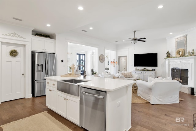 kitchen with ornamental molding, ceiling fan, a center island with sink, a sink, and stainless steel appliances