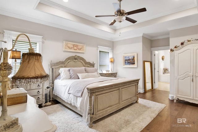 bedroom featuring a ceiling fan, wood finished floors, baseboards, ornamental molding, and a tray ceiling
