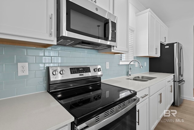 kitchen featuring a sink, appliances with stainless steel finishes, white cabinets, light countertops, and decorative backsplash