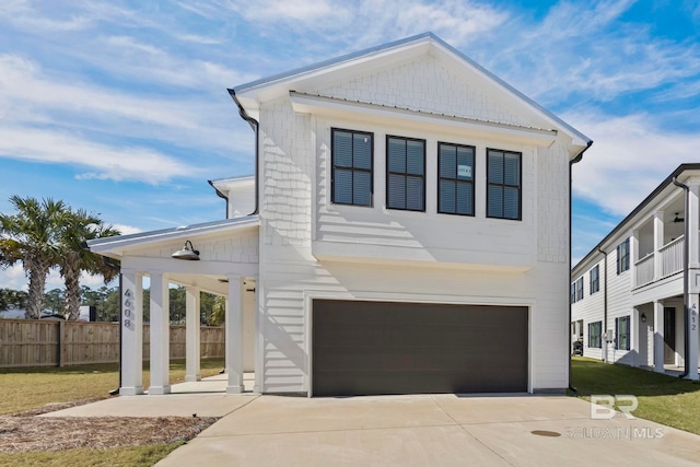 view of front facade with a front lawn, concrete driveway, an attached garage, and fence