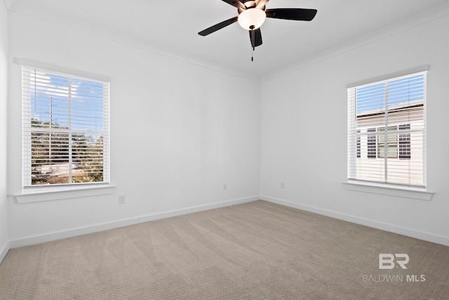 empty room with crown molding, carpet, baseboards, and a healthy amount of sunlight