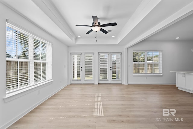 unfurnished sunroom with a tray ceiling, visible vents, and ceiling fan