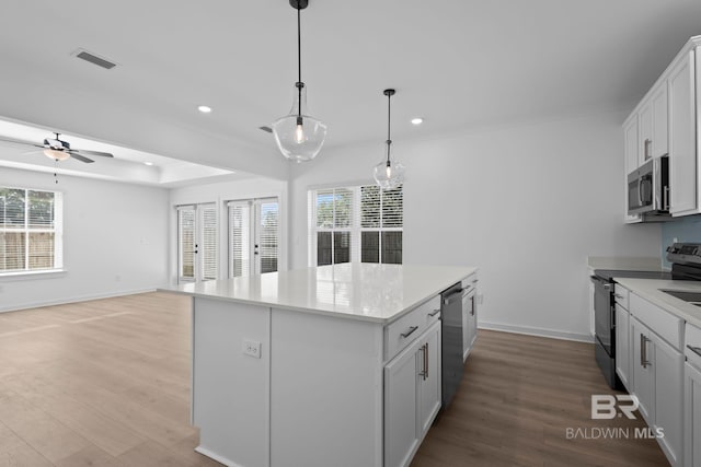 kitchen with recessed lighting, appliances with stainless steel finishes, wood finished floors, and a center island