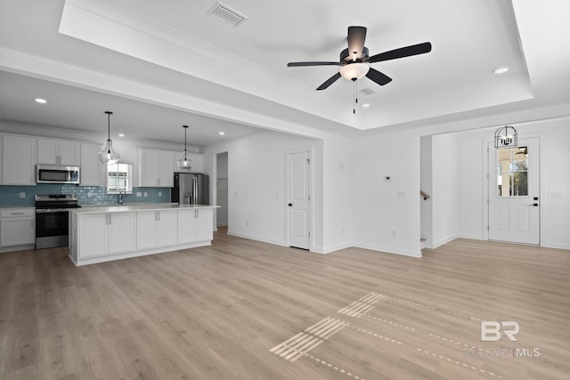 kitchen with open floor plan, visible vents, appliances with stainless steel finishes, and a tray ceiling