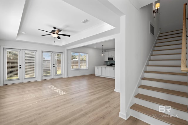 unfurnished living room featuring visible vents, stairs, and a tray ceiling