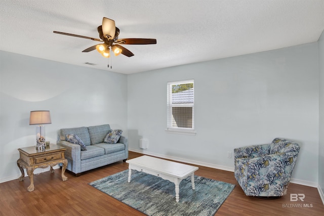 living room with a textured ceiling, ceiling fan, wood finished floors, visible vents, and baseboards