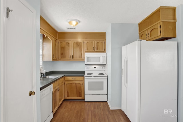 kitchen featuring a textured ceiling, white appliances, wood finished floors, a sink, and visible vents