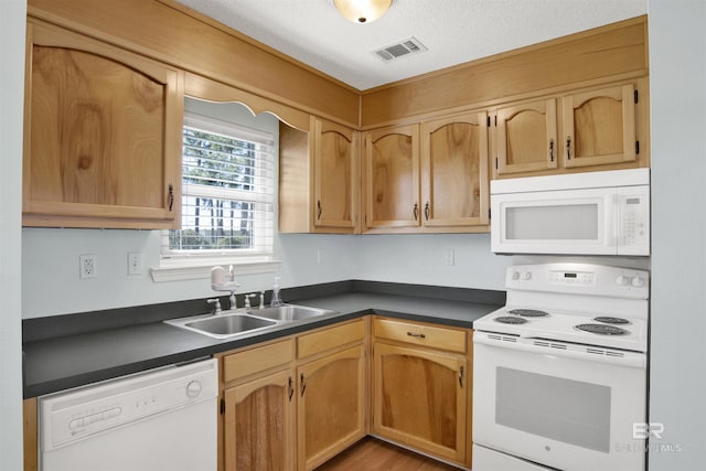 kitchen with white appliances, visible vents, dark countertops, a textured ceiling, and a sink