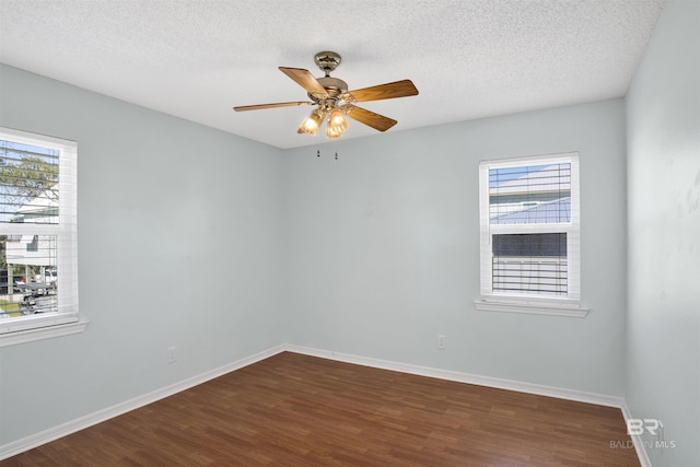 spare room with a textured ceiling, baseboards, dark wood finished floors, and a ceiling fan