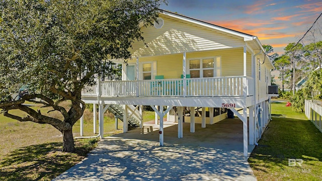 exterior space with a carport, a porch, a lawn, and driveway