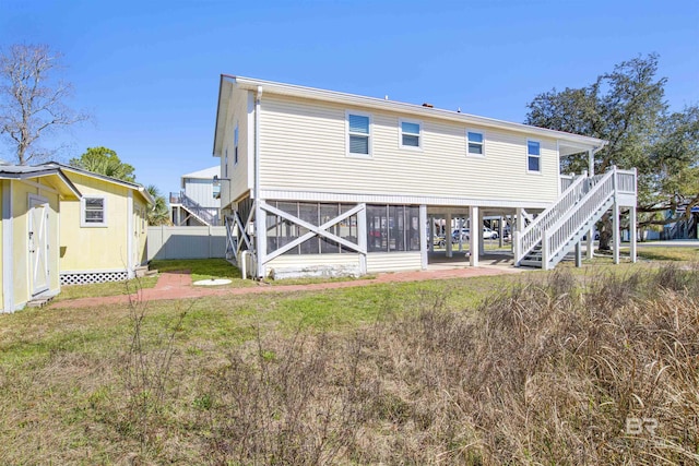 back of property featuring stairs, fence, a lawn, and an outbuilding