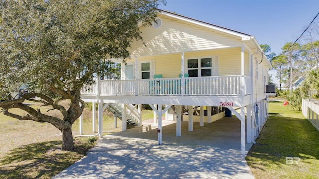 view of front facade featuring a carport, a porch, a front lawn, and driveway