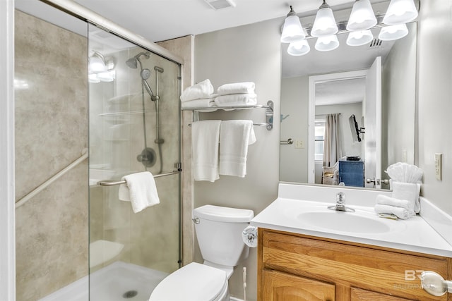 bathroom with vanity, toilet, a notable chandelier, and a shower with shower door