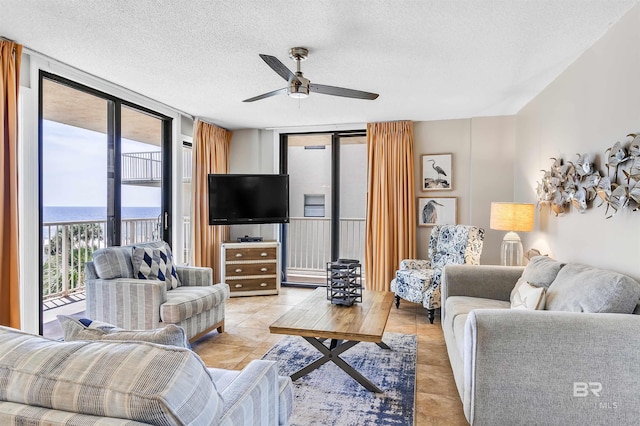 living room featuring a textured ceiling, ceiling fan, light tile patterned floors, and expansive windows