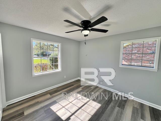 empty room featuring a textured ceiling, ceiling fan, and dark wood-type flooring