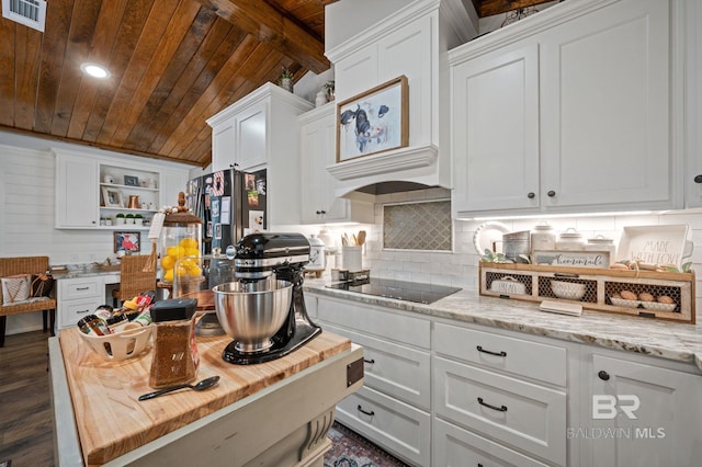 kitchen with black electric stovetop, dark hardwood / wood-style flooring, wooden ceiling, white cabinetry, and stainless steel refrigerator