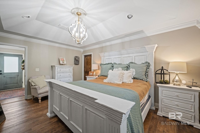 bedroom with dark hardwood / wood-style flooring, ornamental molding, a tray ceiling, and an inviting chandelier