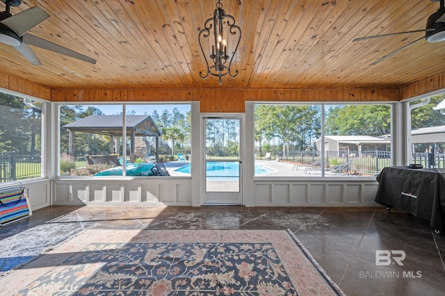 unfurnished sunroom featuring plenty of natural light, wooden ceiling, and ceiling fan with notable chandelier