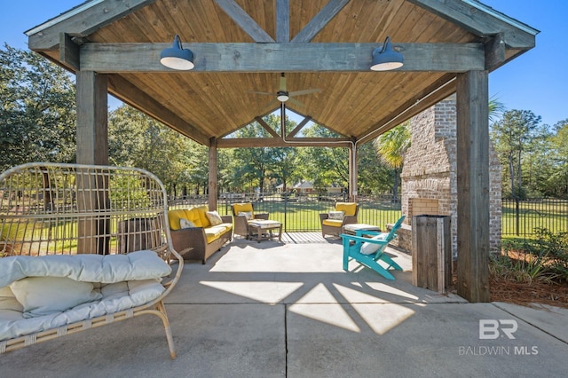 view of patio featuring an outdoor stone fireplace, ceiling fan, and a gazebo