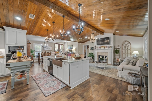 kitchen featuring a kitchen island with sink, white cabinets, lofted ceiling with beams, decorative light fixtures, and dark hardwood / wood-style flooring