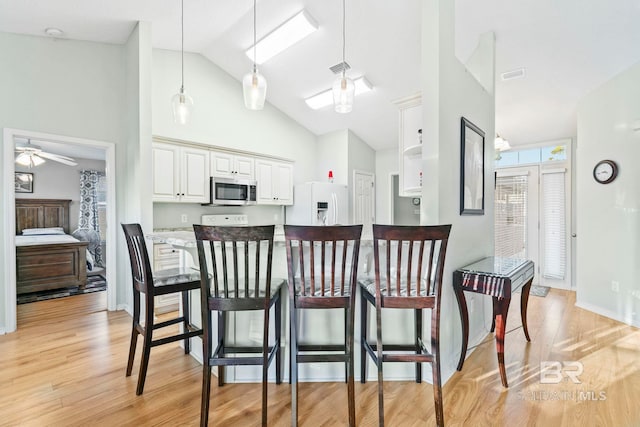 kitchen featuring ceiling fan, white fridge with ice dispenser, white cabinets, light hardwood / wood-style floors, and hanging light fixtures